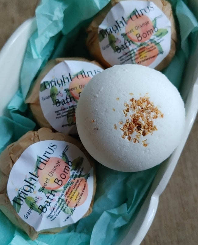 mini ceramic tub with three bright citrus bath bombs one plain and the rest in brown kraft paper essential oil aromatherapy blend