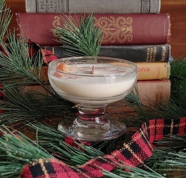 soy wax candle orange essential oil Glass bowl with a candle on a decorative background with books and greenery
