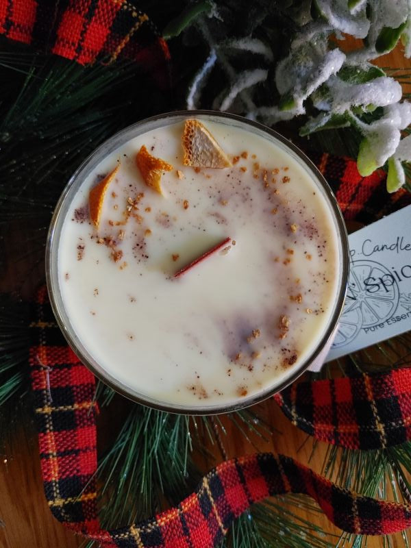 pure soy wax essential oil orange and spice candle  with decorative elements on a plaid cloth housed in glass cocktail glass
