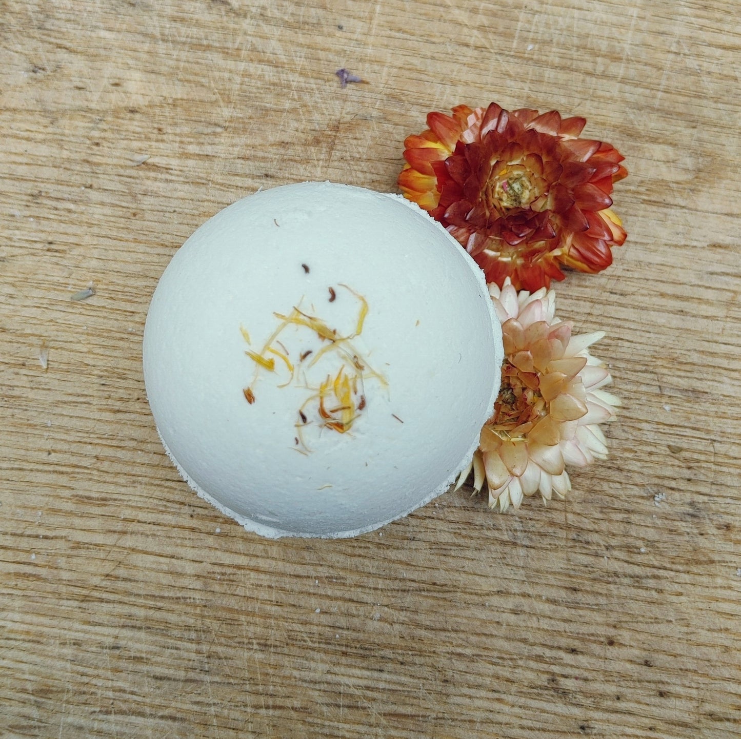 White bath bomb with floral elements on a wooden surface
