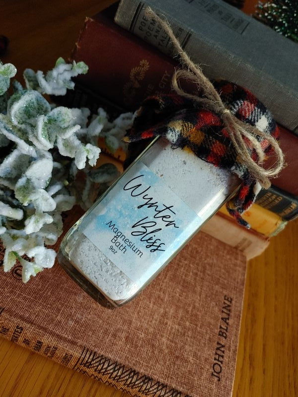 winter blues fighter magnesium body soak salt Jar of 'Winter Bliss' bath salt on a wooden surface with books and a plant.