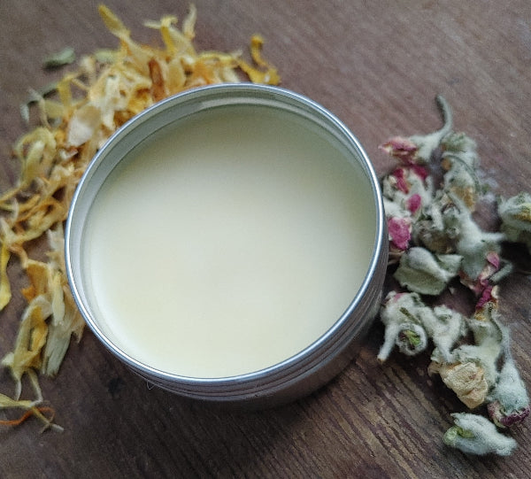 beeswax ip balm infused with grapefruit essential oil on a wooden background with dries florals