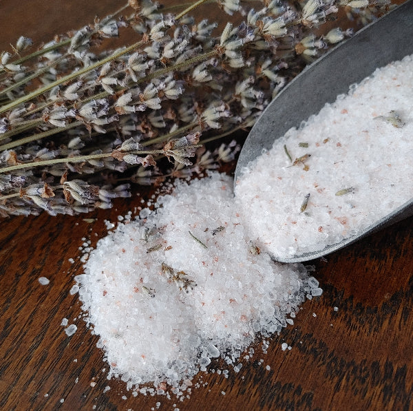 lavender bath salt body soak with metal scoop and dried lavender buds displayed on wood background essential blends