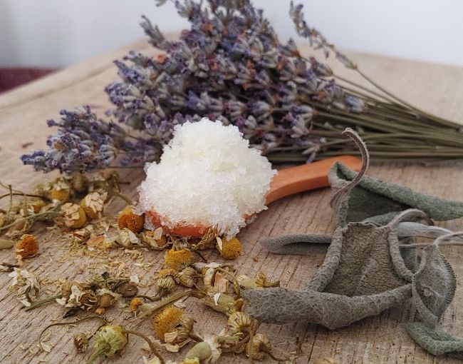 theraptuic salt and sugar body scrub on wooden surface with dried flowers