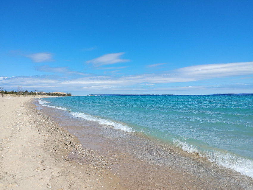 sandy beach with blue freshwater wispy white clouds over lake michigan in glen arbor michigan
