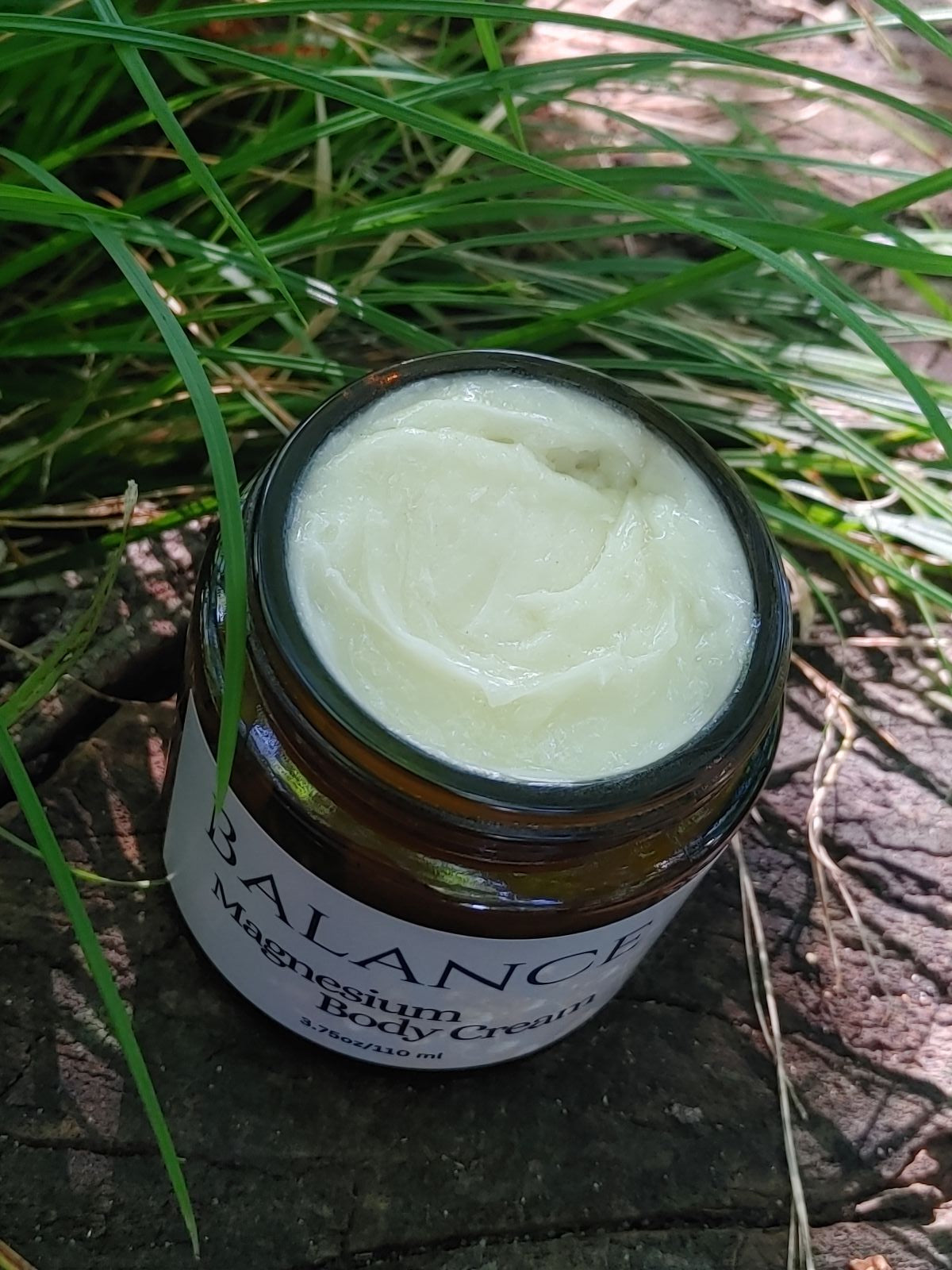 Jar of cream labeled 'Balance' on a wooden surface with grass