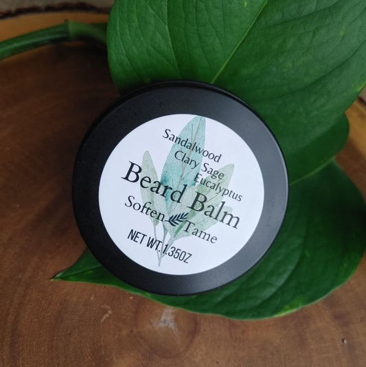 Beard balm container with a black lid on a green leaf sandalwood eucalyptus sandalwood scented beard care