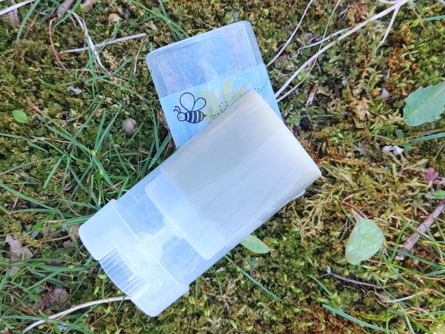plant based insect bite relief salve Transparent plastic container with a label on a grassy background