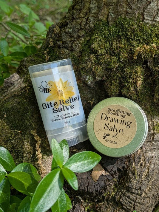 Two containers of Bite Relief Salve on a tree stump with greenery
