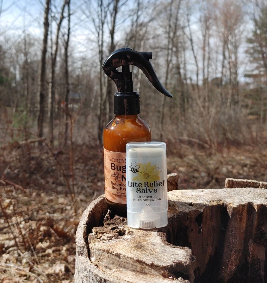 Two bottles of natural products on a wooden stump in a forest setting.