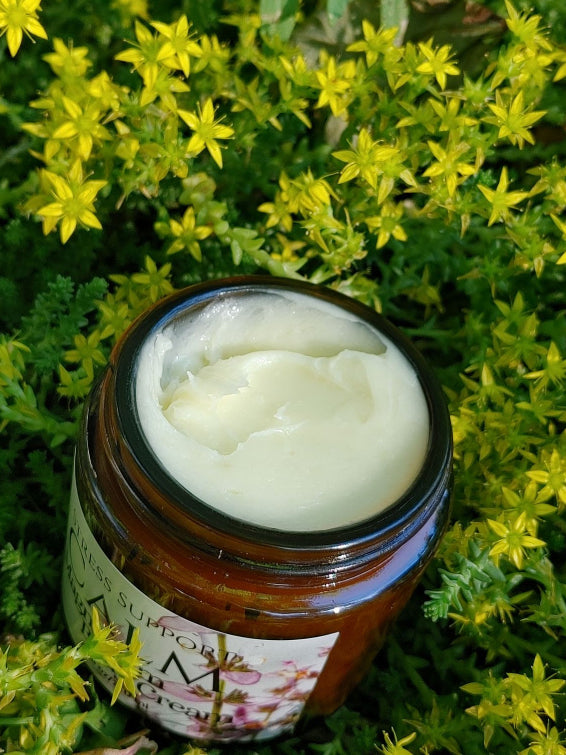 Jar of calming magnesium body cream with a floral label on a green and yellow herbal plant background