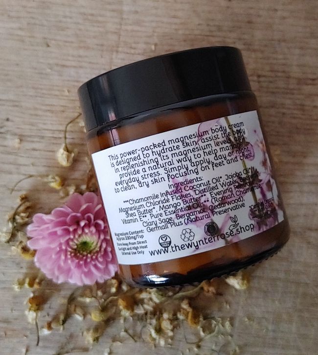 Jar of body cream with a label on a wooden surface with flowers