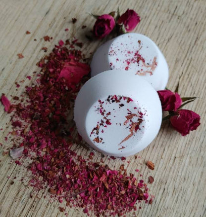 Two white rose shower steamers with floral decorations on a wooden surface with dried flowers and roses.