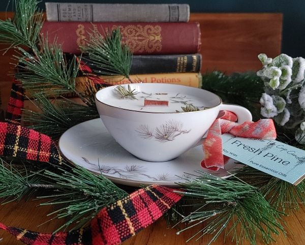pine needle scented soy wax candle in vintage Teacup with Christmas decorations on a wooden surface