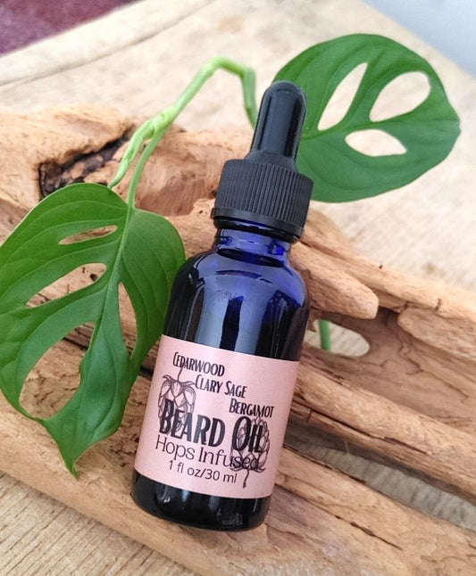 Bottle of beard oil with a dropper on a wooden surface with leaves in the background cascade hops infused beard care