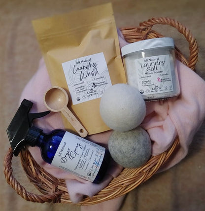Collection of natural laundry products including a spray bottle, laundry wash, dryer balls, and laundry salt in a basket.