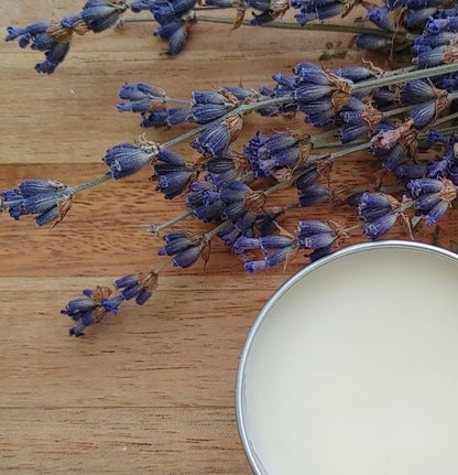 Lavender flowers on a wooden surface with a container of lavender infused lip balm plant based lip care