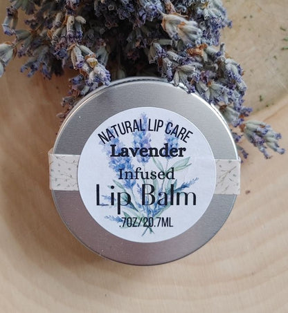 Lavender infused lip balm with a label on a wooden surface with lavender flowers.