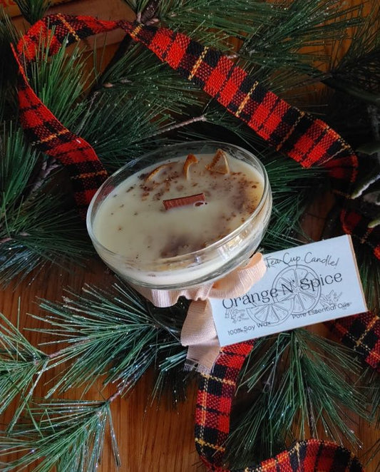 Holiday candle soy wax Candle in a glass holder with 'Orange N Spice' label on a Christmas wreath.