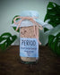 Bottle of 'Period' magnesium bath salt menstrual PMS symptom relief bath soak with a label on a wooden surface with green leaves in the background.