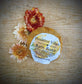 Bath bomb with a label reading 'Positive Vibes' surrounded by flowers on a wooden surface