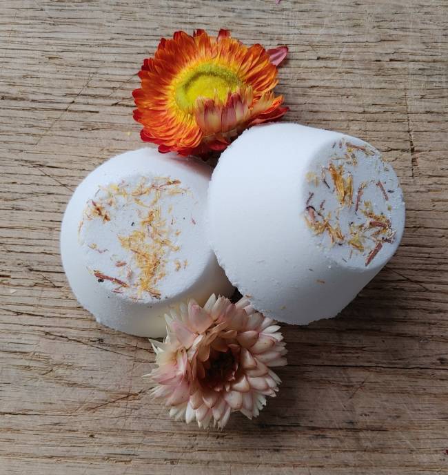Two floral shower steamers with floral elements on a wooden surface. essential oil aromatherapy for the shower