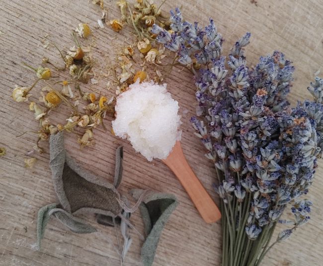 Herbal bath salts with lavender and other herbs on a wooden surface