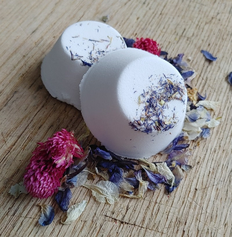 mood lifting sigh and smile shower steamer with gardenia and ylang ylang sitting with dried flowers on a wooden backdrop