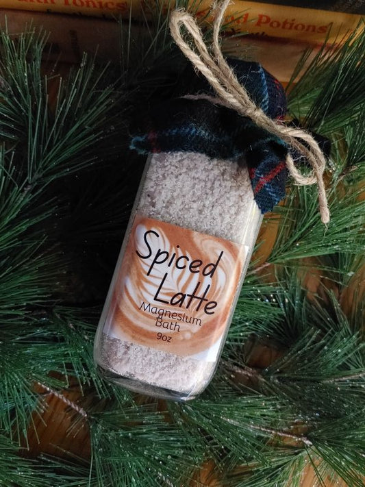 Spiced Latte magnesium salt body soak mix in a decorative container with a label on a green leafy background