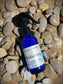 refreshing hydrating peppermint cooling mist body spray witch hazel blue glass spray bottle on beach stone sand in michigan glen arbor