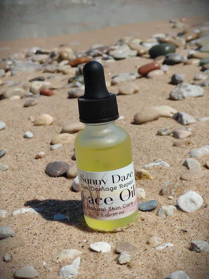 sunny daze face oil plant based summer face care sun repair carrot seed oil raspberry seed oil frosted glass dropper bottle on sandy beach stone michigan beach sleeping bear dunes