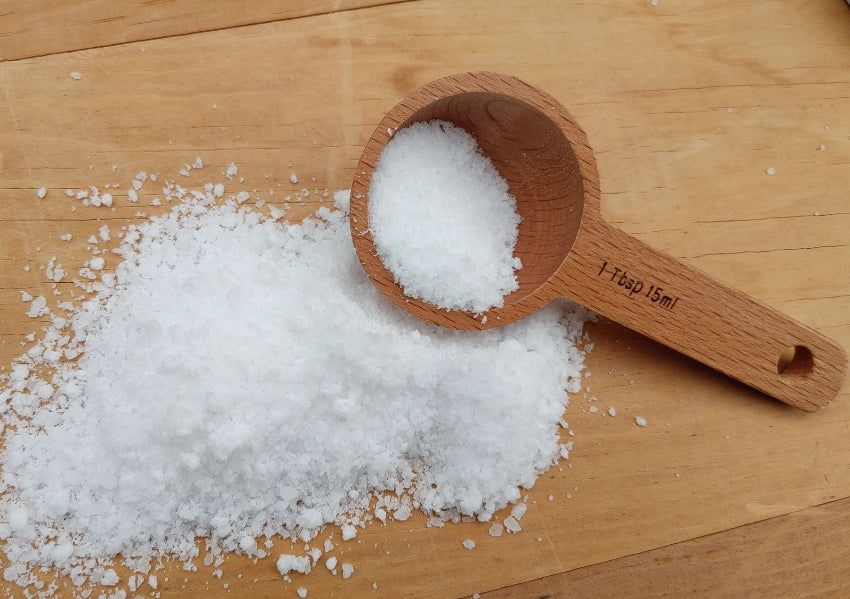 Wooden Tablespoon with laundry detergent powder ona wood surface