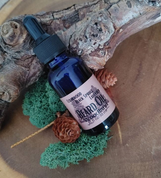 Bottle of woodland beard oil with a label on a wooden surface with pine cones and greenery.